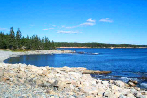 Another pebbly rocky beach with a sailboat afar